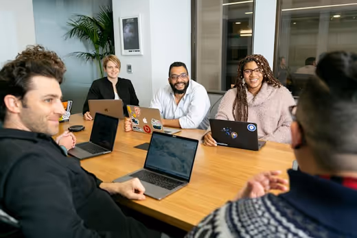 Four people from an agency around a table, laptops open.